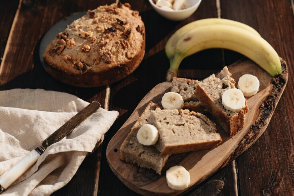 Banana bread with banana slices on a wooden table