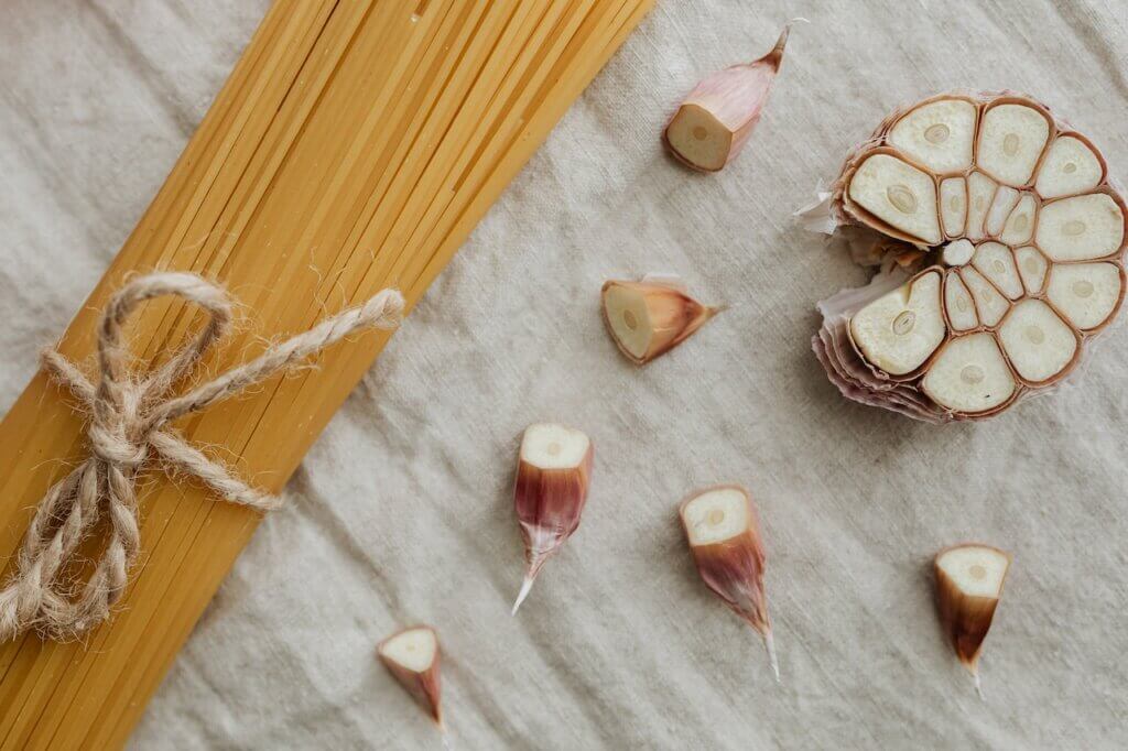 Pasta noodles next to garlic cloves
