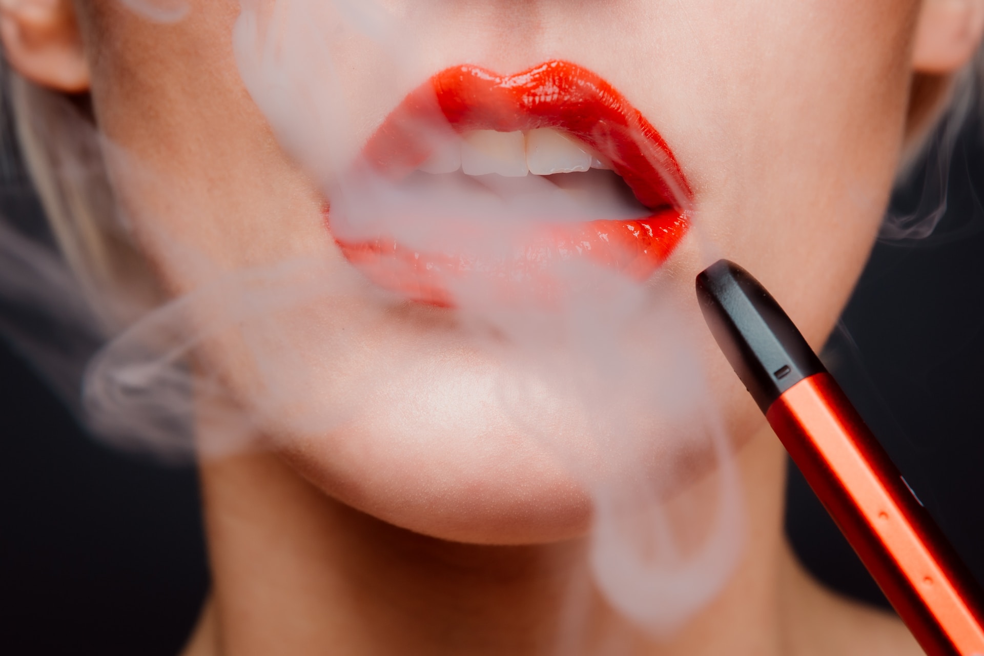 Woman with red lips uses a vape